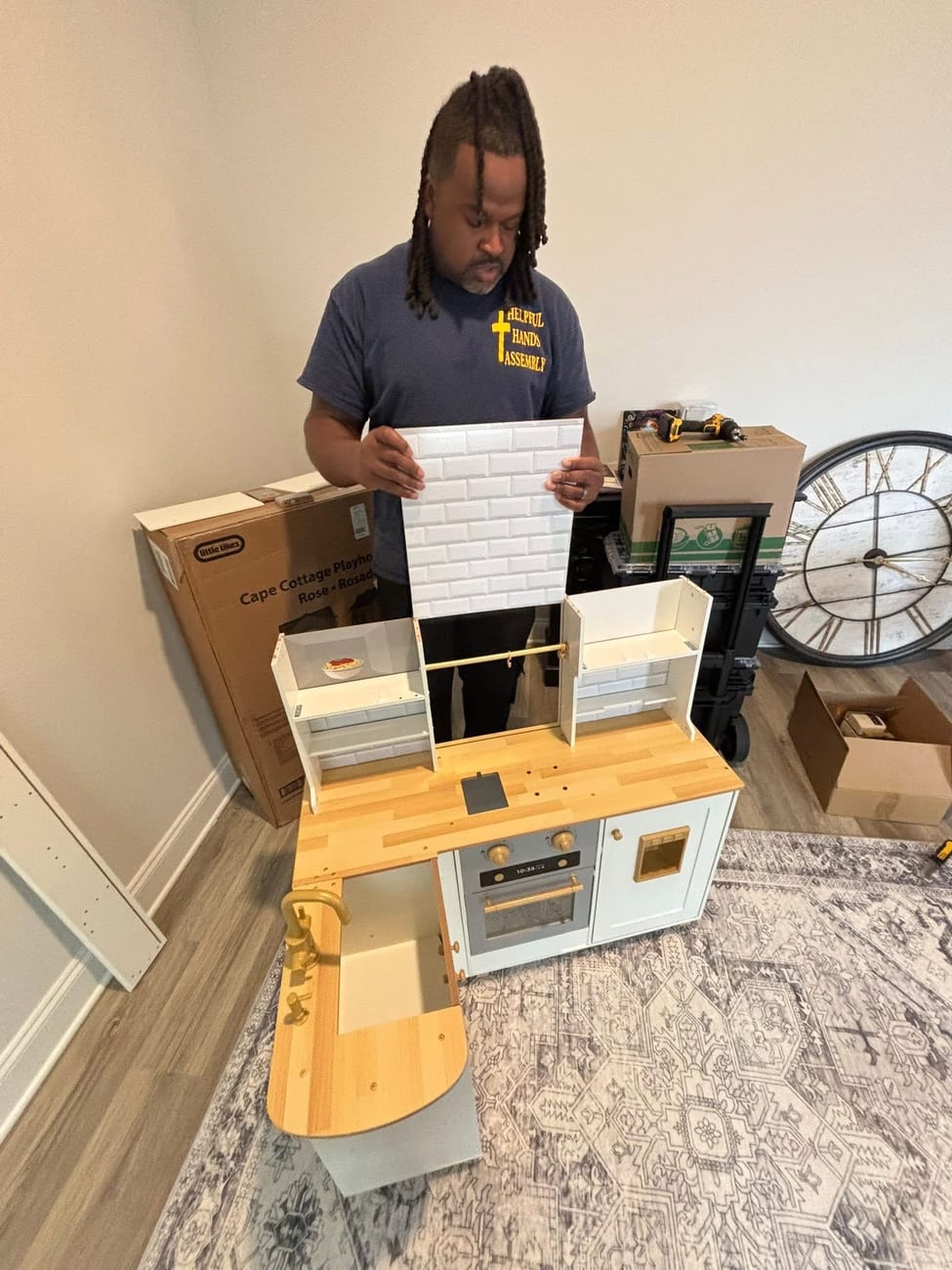 Reuben Buford in his Helpful Hands Assembly shirt assembling a play kitchen
