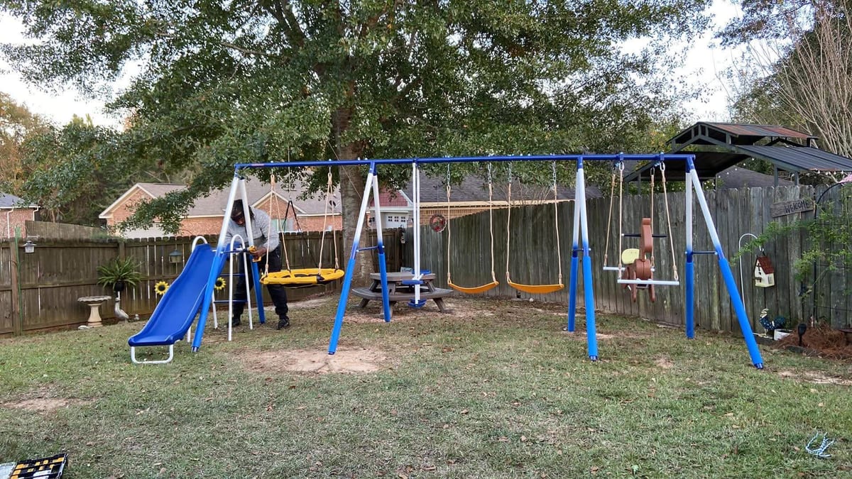 Metal swing set with slide being assembled